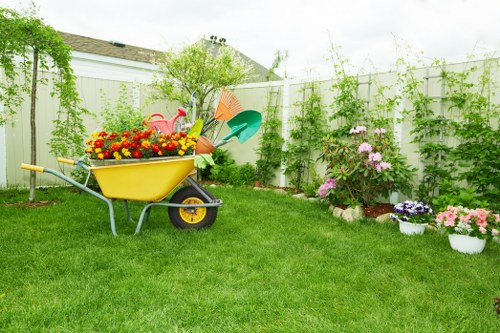 Operative using protective gloves and safety boots while trimming hedges